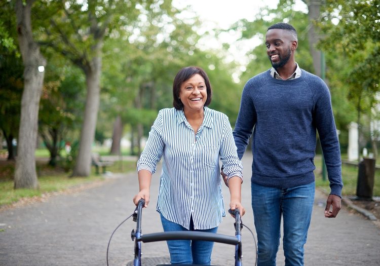 man walking with an older woman using a walker outdoors