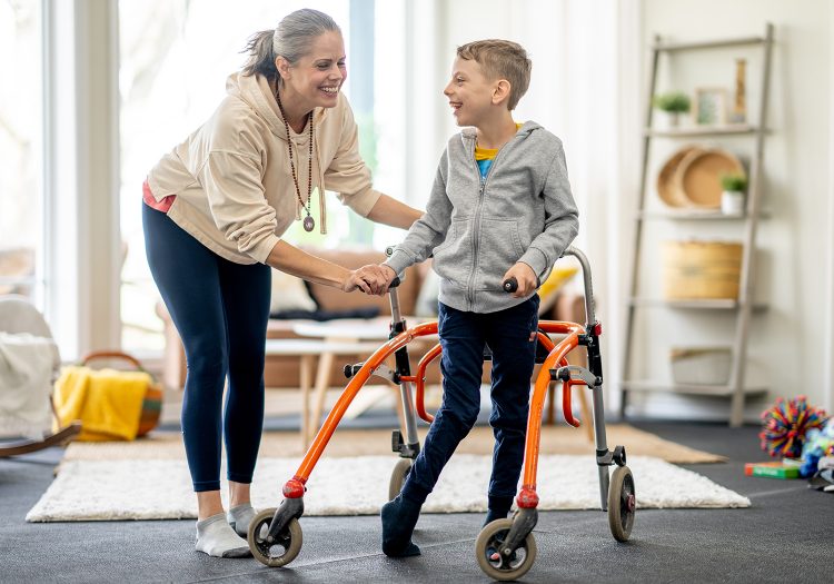 woman helping a young boy use his walker